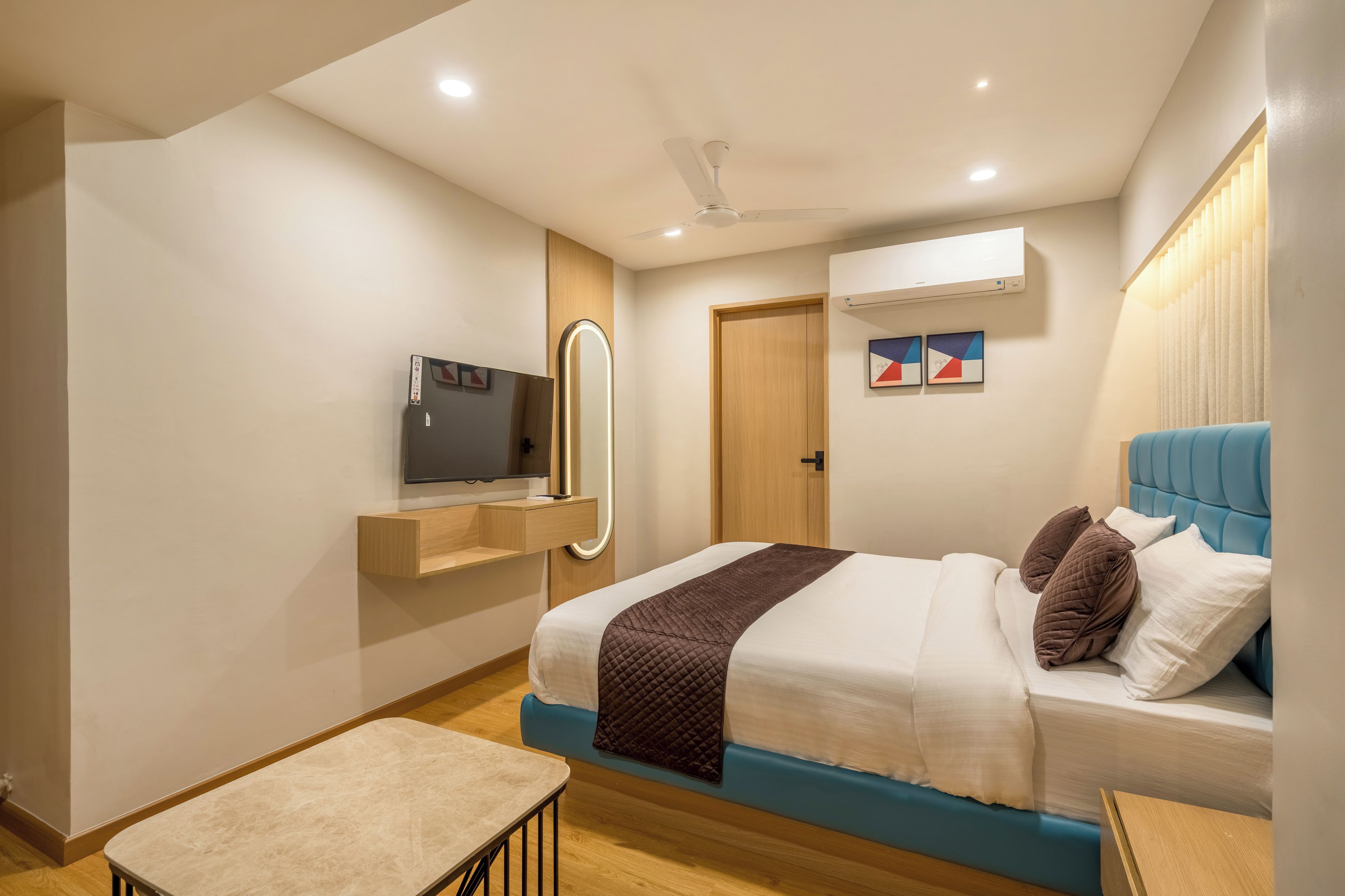 A modern bedroom with a bed, bedside table, mirror, and a ceiling fan.