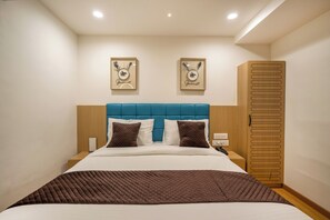 Une chambre d’hôtel comprenant un lit, une table de chevet, une armoire et deux œuvres d’art accrochées au mur.