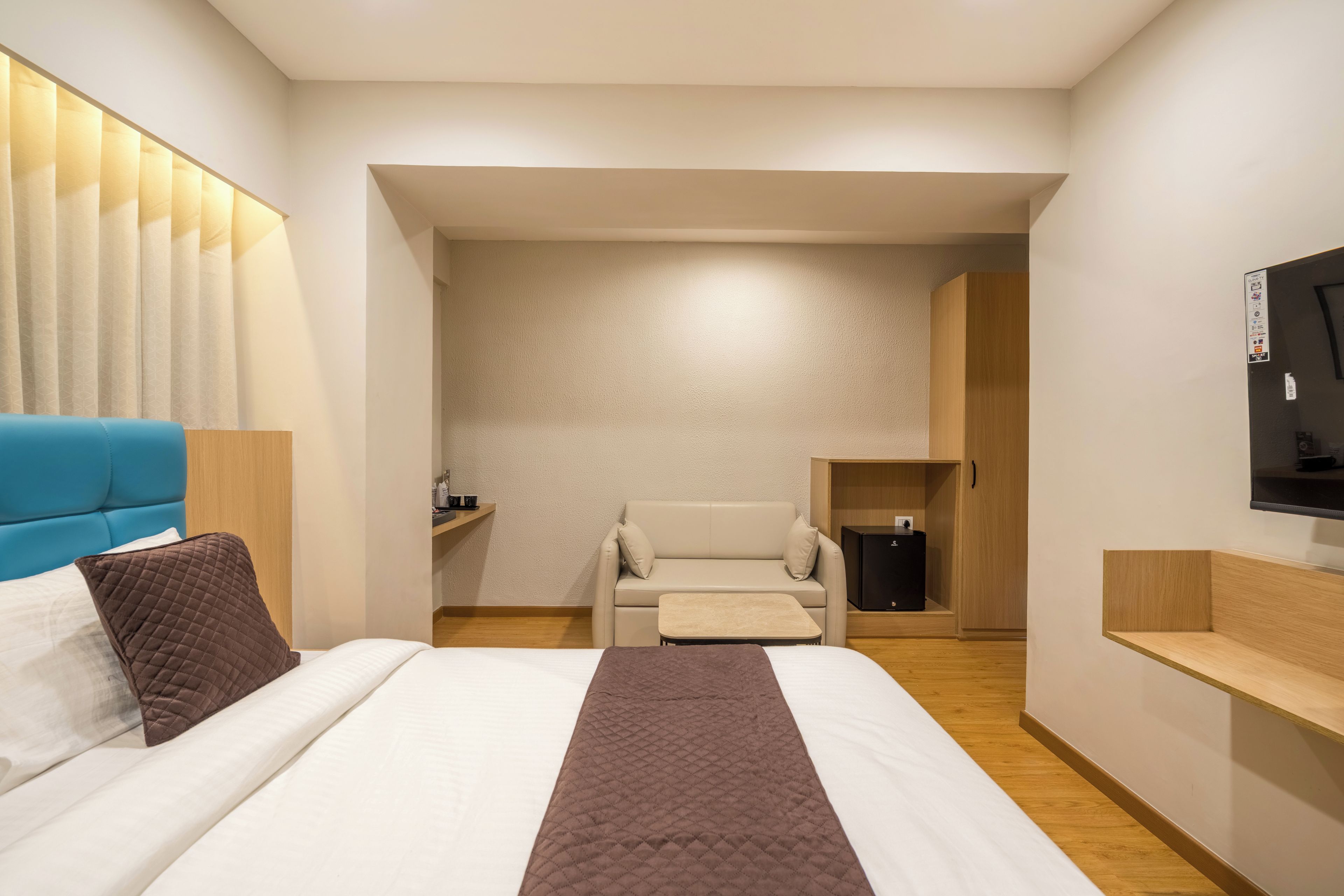 Een hotelkamer met een bed, een slaapbank, een televisie en een tafeltje.