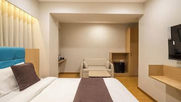 Een hotelkamer met een bed, een slaapbank, een televisie en een tafeltje.
