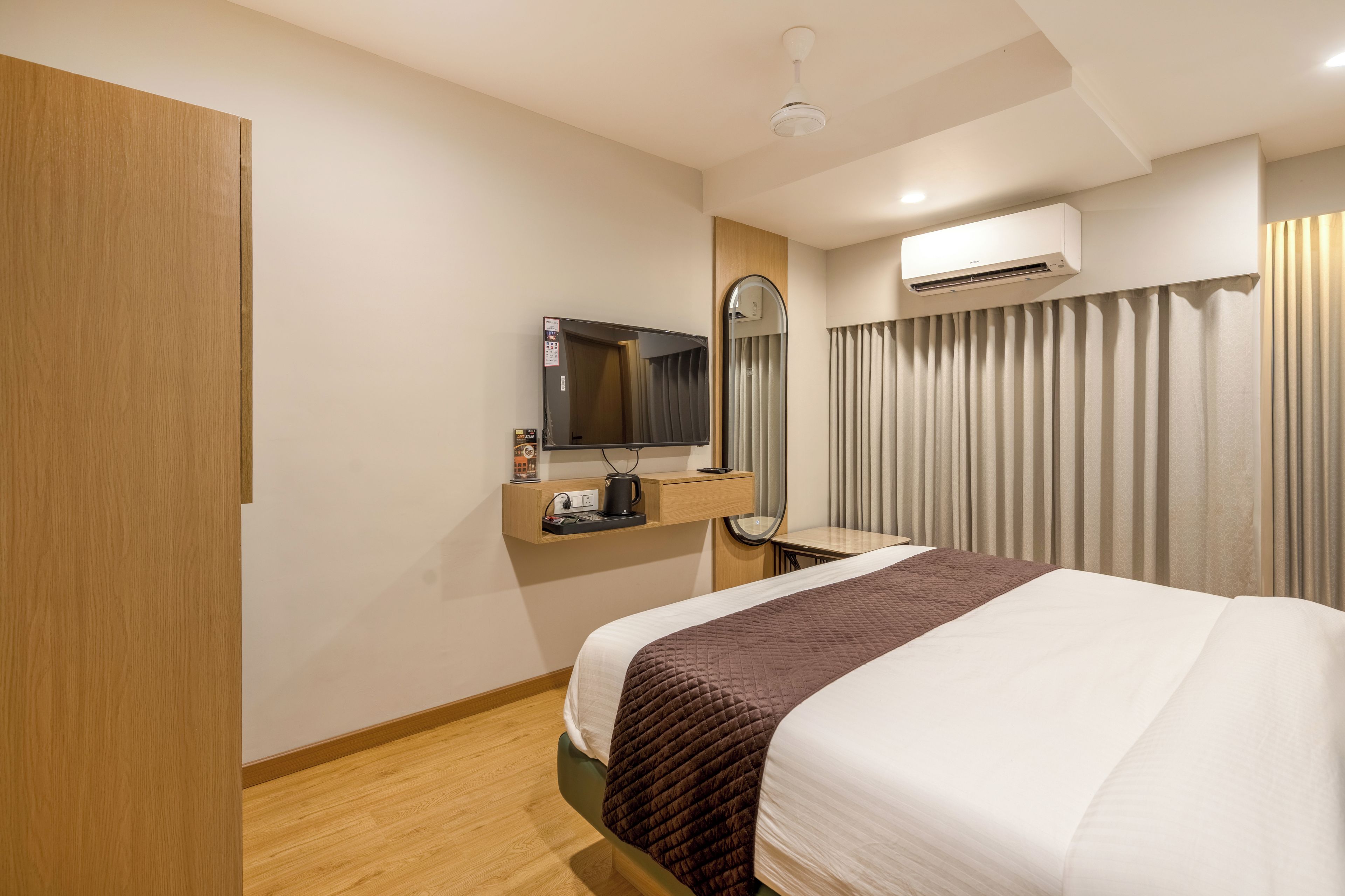 Habitación de hotel con cama, escritorio con espejo, aire acondicionado y armario.