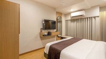 Habitación de hotel con cama, escritorio con espejo, aire acondicionado y armario.