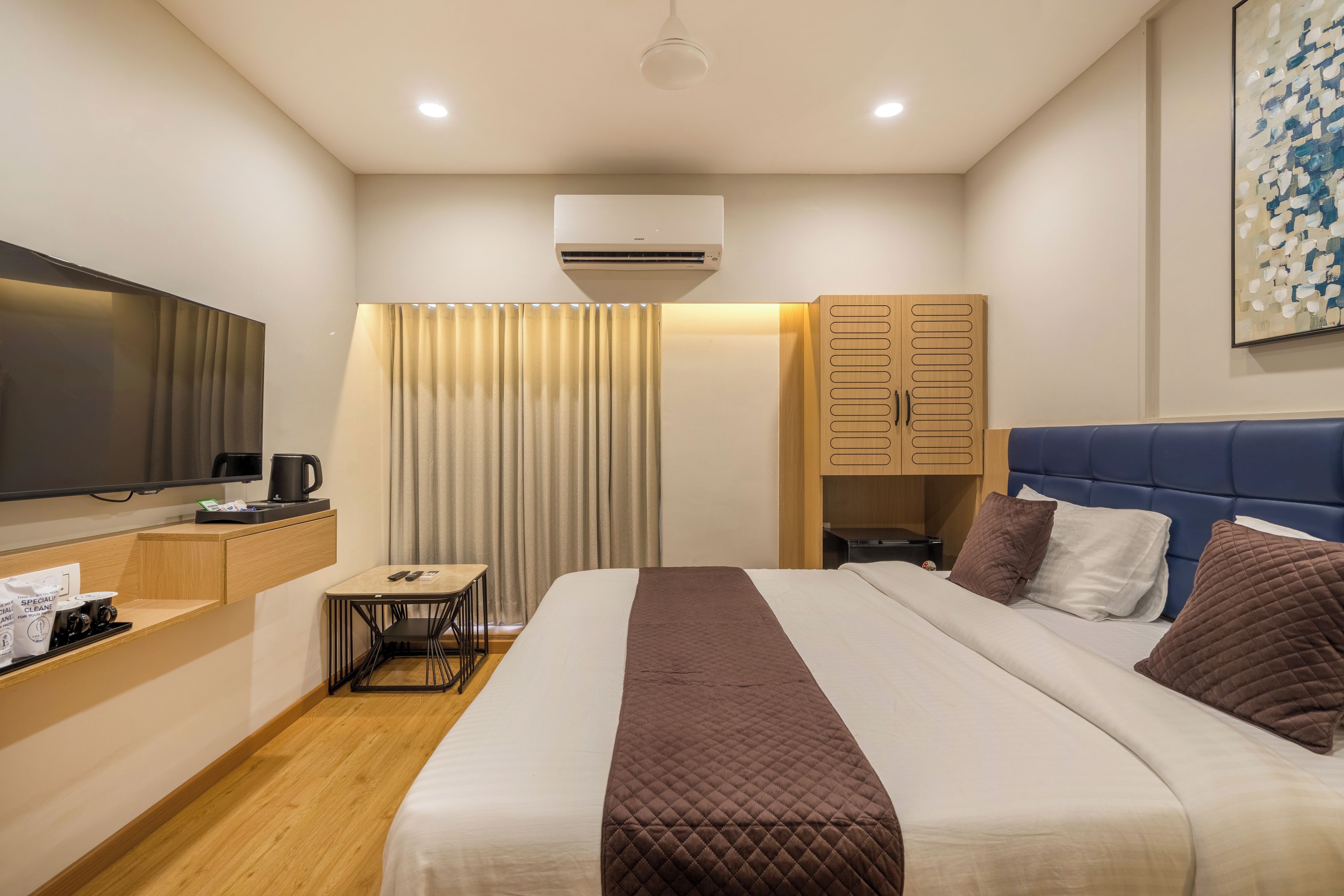 Une chambre d’hôtel équipée d’un lit, d’un bureau, d’une télévision et d’une armoire.