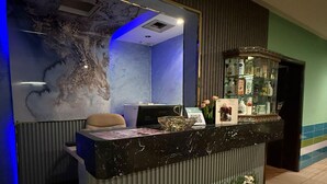 A reception desk with a marble top, a chair, a wall-mounted mirror, and a decorative glass cabinet with items. - Suites by Sunday Avenue in the Heart of Riyadh (Riyadh)