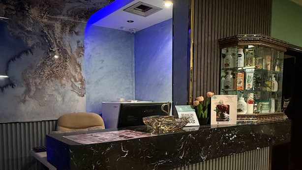 A reception desk with a computer, a chair, and a glass display case with various items. - Suites by Sunday Avenue in the Heart of Riyadh (Riyadh)