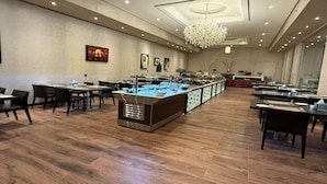 A spacious dining area with multiple tables and chairs, a central buffet station, and a chandelier. - Suites by Sunday Avenue in the Heart of Riyadh (Riyadh)