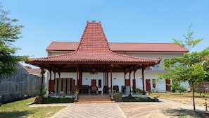 A traditional building with a red-tiled roof, a central pavilion, and a paved entrance area.