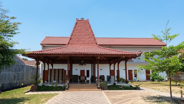A traditional building with a red-tiled roof, a central pavilion, and a paved entrance area.