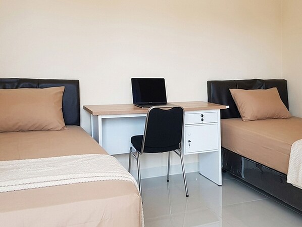 A room with two beds, a desk with a laptop, and a chair.