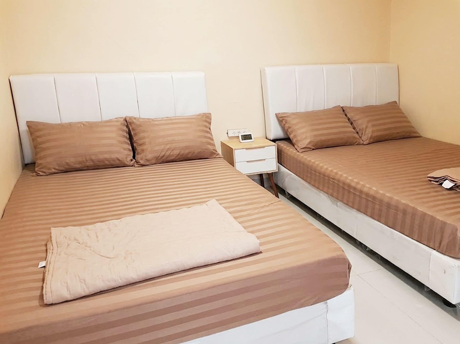A hotel room with two beds, a nightstand, and a folded towel.