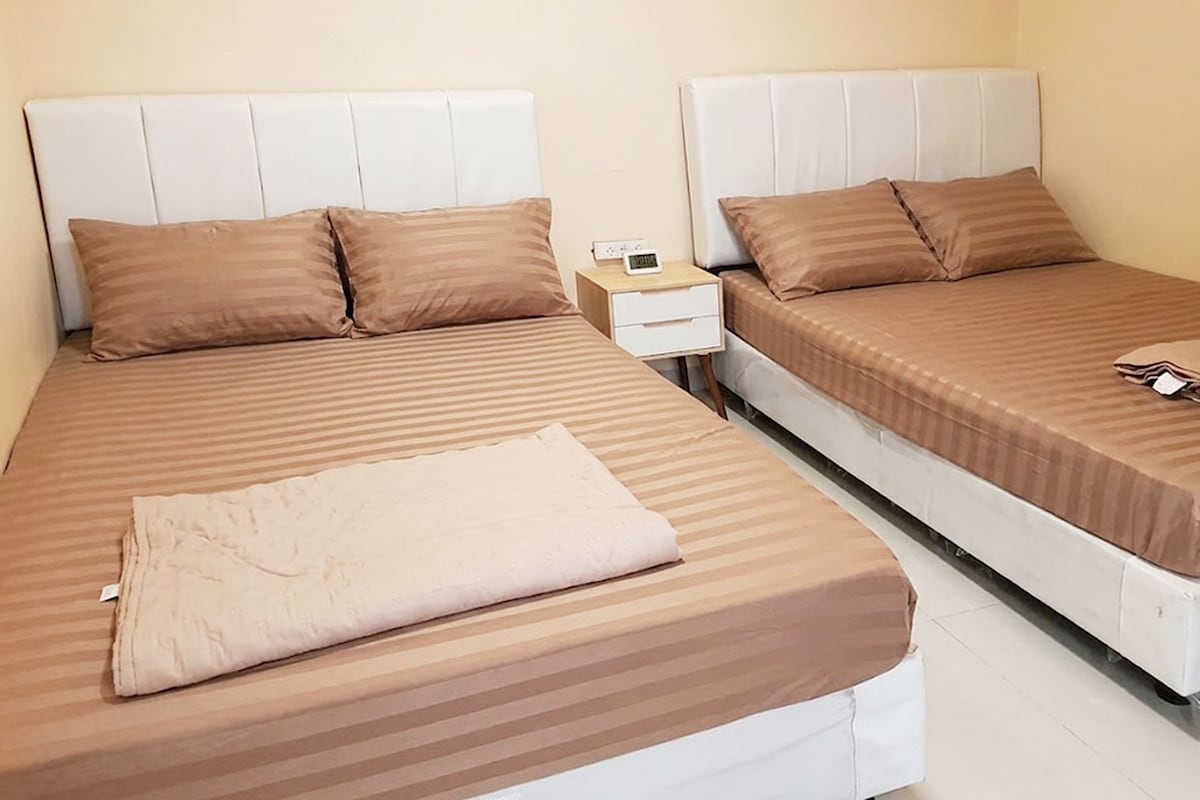A hotel room with two beds, a nightstand, and a folded towel.