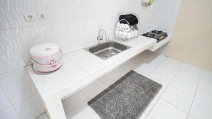 Una cocina con encimera blanca, un lavabo, un escurreplatos y un hervidor.