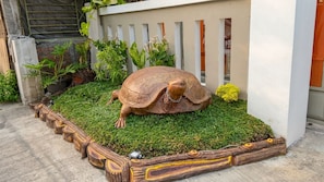 A garden with a large turtle sculpture surrounded by greenery and a decorative border.