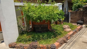A garden area with a sign, a brick pathway, and a variety of plants.