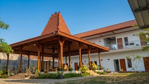 A building with a covered patio area, a balcony, and a tiled roof.