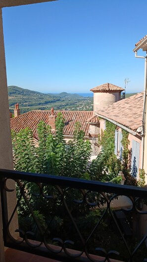 Ein Balkon mit Blick auf Häuser mit Terrakotta-Dächern und eine weite Landschaft.