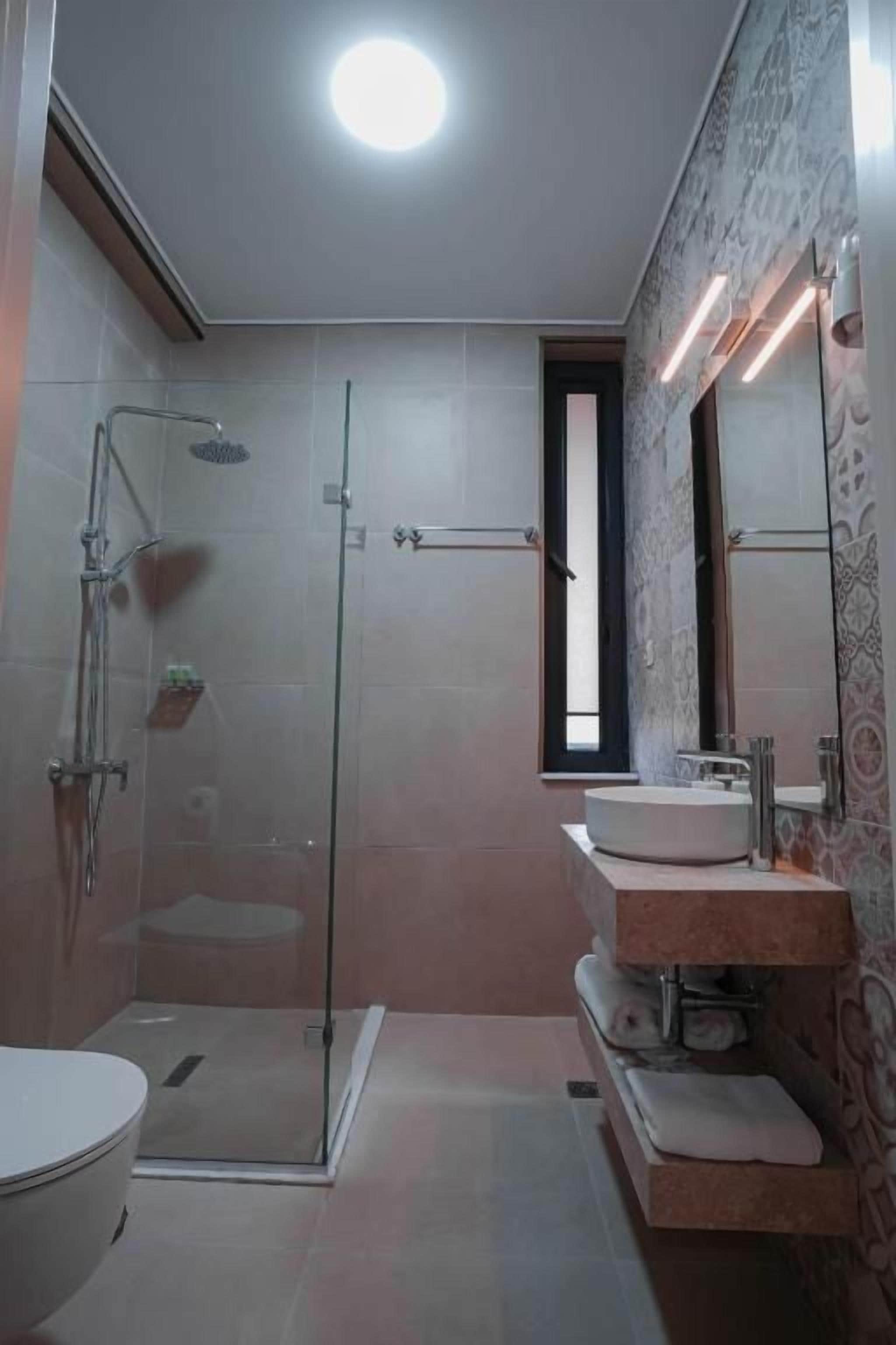 Un baño con cabina de ducha de vidrio, inodoro y tocador con espejo.