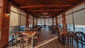 A spacious indoor dining area with brick walls, wooden tables and chairs, and large windows. - Mikheilis Marani Boutique Hotel  (Kvareli)
