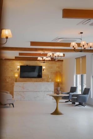 Una sala de estar moderna con chimenea, un televisor de pantalla plana montado en una pared de piedra y una mesa redonda dorada.