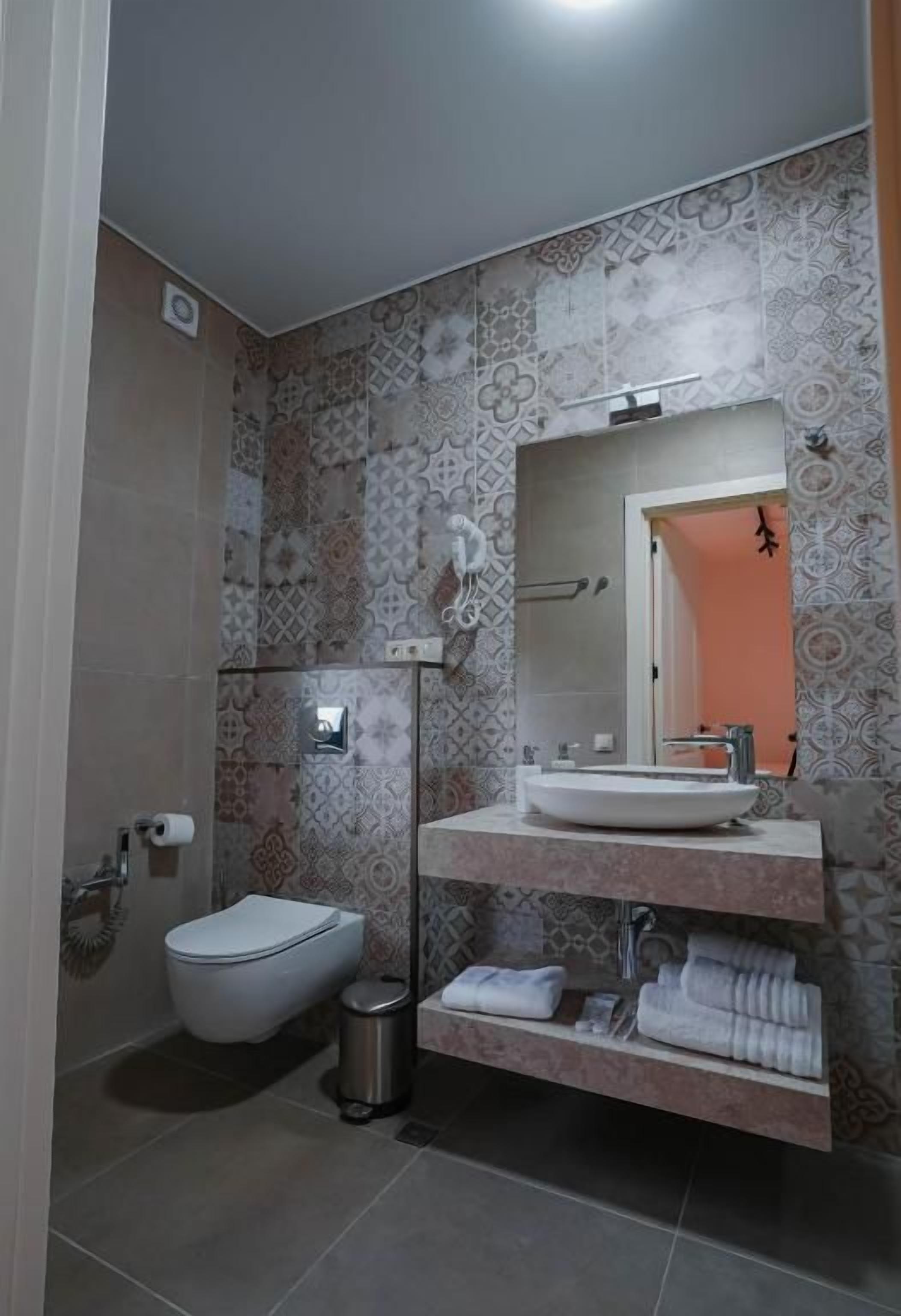 Un baño con inodoro, lavamanos y toallero.