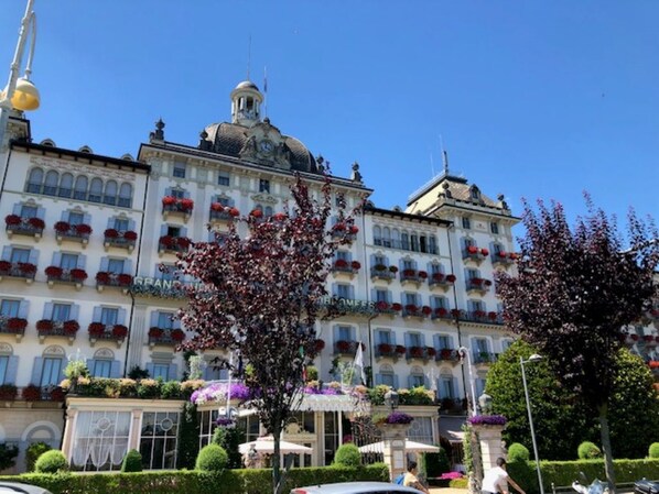 A large hotel with multiple floors, balconies with red flowers, and a dome on the top.