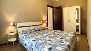 Et soveværelse med seng, sengeborde, en garderobe og en dør.