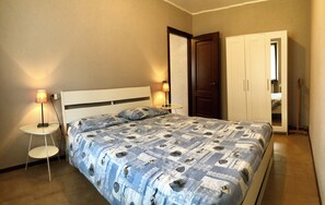 Een slaapkamer met een bed, nachtlampjes, een kledingkast en een deur.