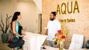 A reception area with a brick wall and a sign that reads 'AQUA Luxury Suites.' - AQUA Boutique Hotel- Ocean View Suites (Glacis)