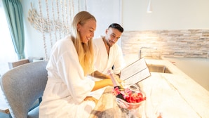 A couple in a modern bathroom with a stone wall, a sink, and a decorative plant. - AQUA Boutique Hotel- Ocean View Suites (Glacis)