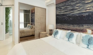 A bedroom with a bed, a nightstand, a lamp, a large window, and a view of the ocean. - AQUA Boutique Hotel- Ocean View Suites (Glacis)