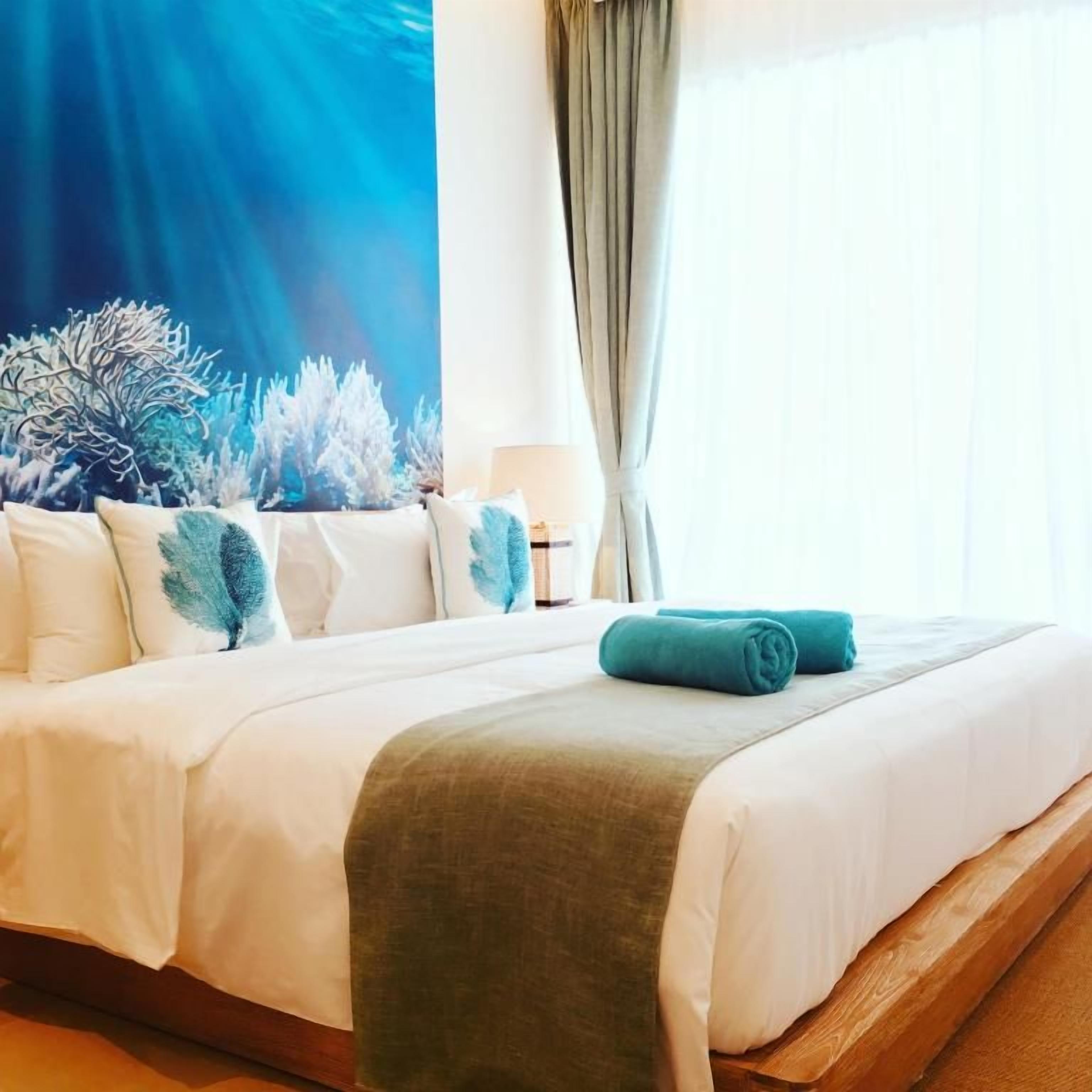 A hotel room with a bed, a large wall tapestry, and a window with curtains.