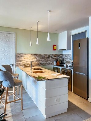 A modern kitchen with a central island, pendant lighting, and a built-in oven.