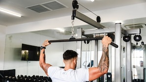 A person performing a pull-up exercise on a gym machine. - AQUA Boutique Hotel- Ocean View Suites (Glacis)