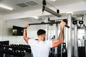 A person performing a pull-up exercise on a gym machine. - AQUA Boutique Hotel- Ocean View Suites (Glacis)