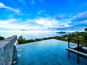 Una piscina infinita con vistas despejadas al mar y la costa lejana.