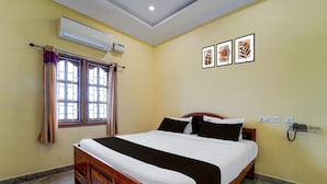 A hotel room with a bed, an air conditioning unit, a window with curtains, and a wall-mounted phone. - Hotel O Karaikal Beachview (Karaikal)
