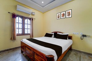 Habitación de hotel con cama, equipo de aire acondicionado, ventana con cortinas y teléfono en la pared.