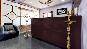 A hotel reception area with a reception desk, a ceiling fan, a wall-mounted sign, and a decorative lamp. - Hotel O Karaikal Beachview (Karaikal)