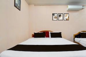 Una habitación de hotel con una cama, una mesita de noche y un equipo de aire acondicionado.