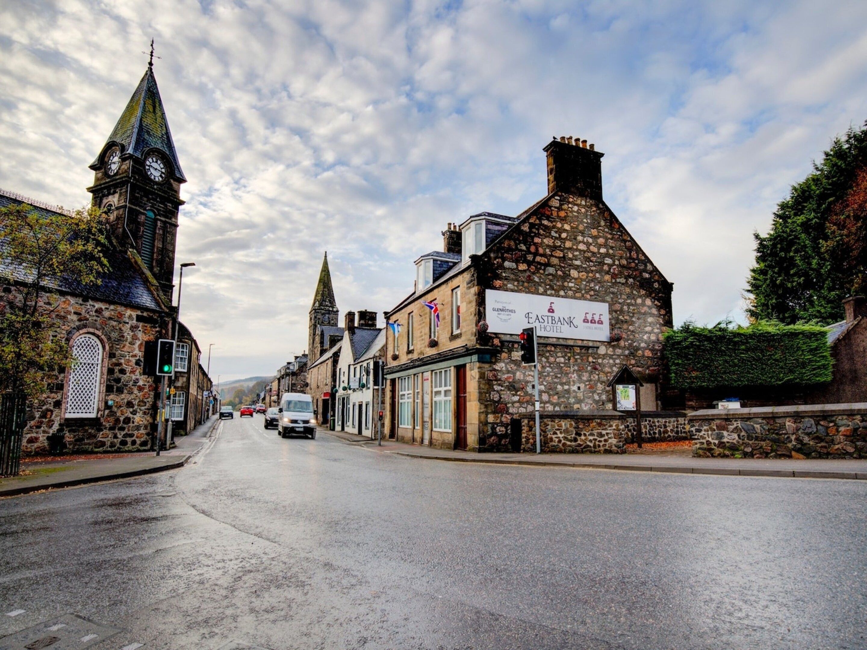 A street view with a historic building featuring a stone facade and a clock tower.