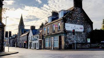 A street view with a hotel named 'Eastbank Hotel' and '3 Still Hotel' with stone facades, a church spire, and a clear sky.