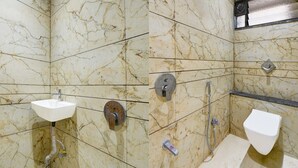 Et badeværelse med marmorvægge, vask, toilet og brusebad.