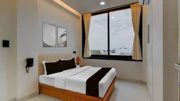 A modern bedroom with a bed, a phone, artwork, a window with curtains, and a city view.