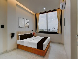 A modern bedroom with a bed, a phone, artwork, a window with curtains, and a city view. - Collection O Aurangabad Shendra Midc (Chhatrapati Sambhajinagar)