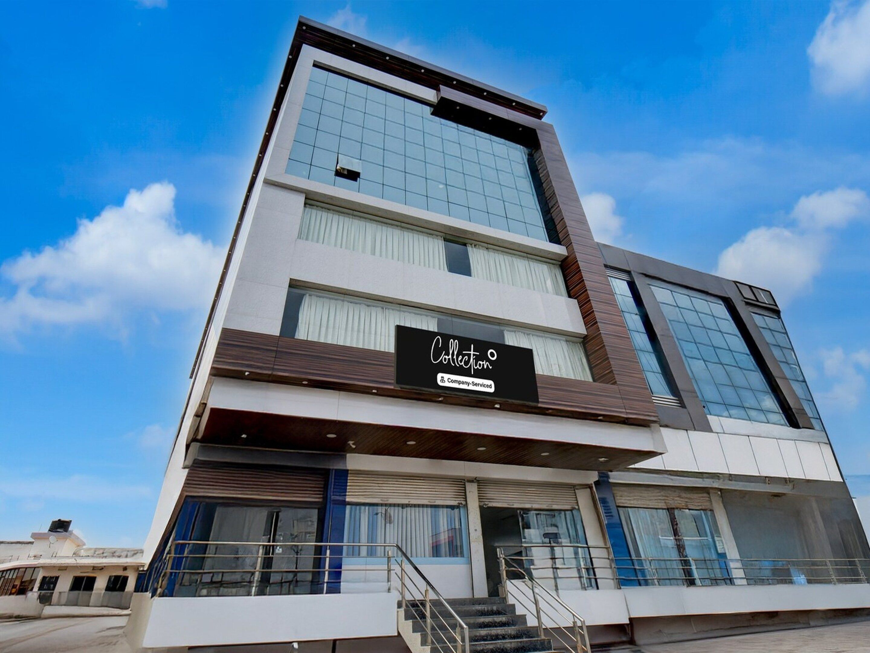 A modern building with a sign reading 'Collection' and a staircase leading to the entrance.