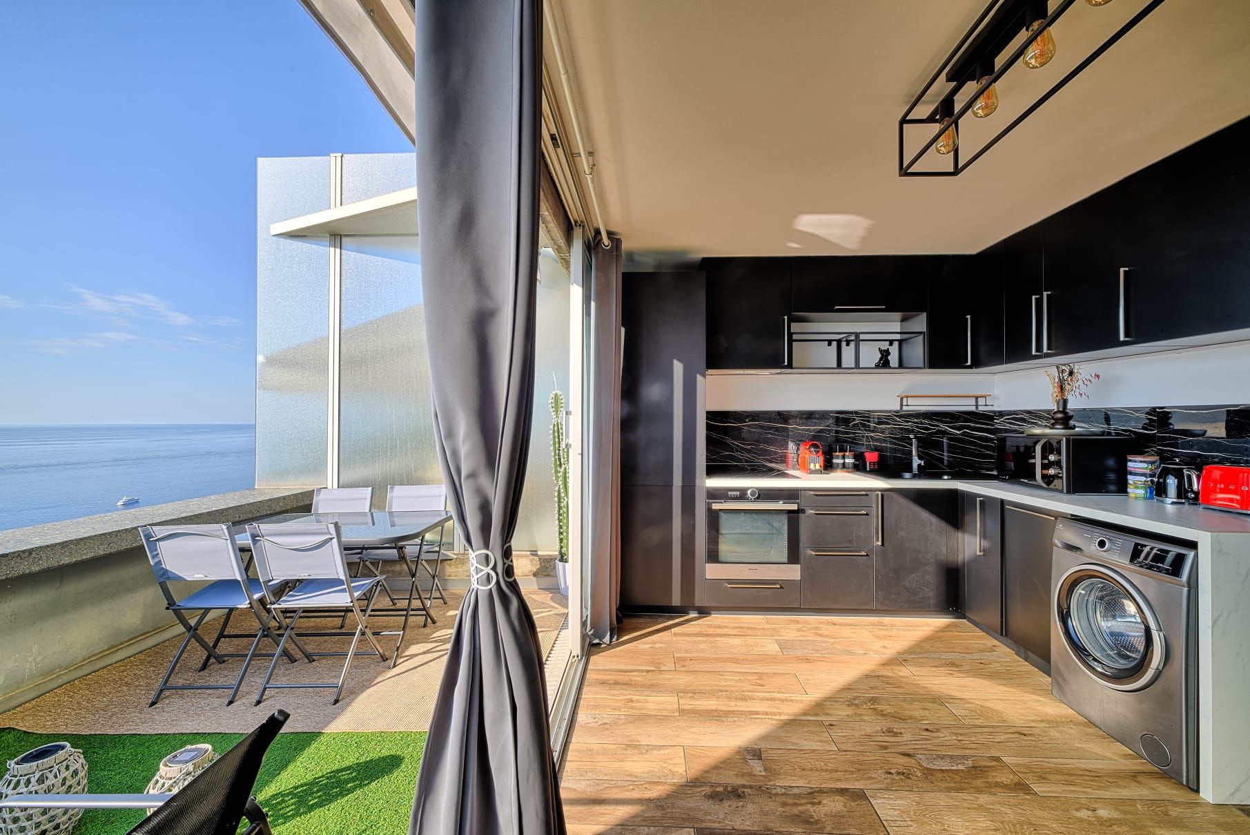 Une cuisine moderne avec vue sur la mer, un lave-linge et un coin repas avec des chaises.