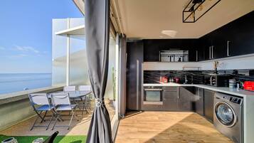 Une cuisine moderne avec vue sur la mer, un lave-linge et un coin repas avec des chaises.