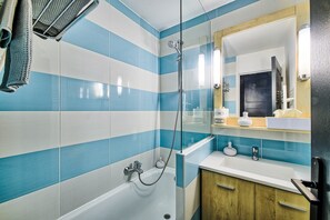 Une salle de bain équipée d’une douche, d’une baignoire et d’un meuble-lavabo avec un miroir.