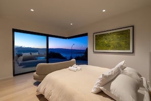 Ein Schlafzimmer mit einem großen Bett, einer Couch und Blick ins Freie.