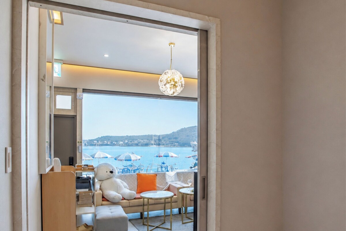 Een slaapkamer met een groot bed, uitzicht op een balkon met tuinmeubilair en een stadsgezicht op de achtergrond.